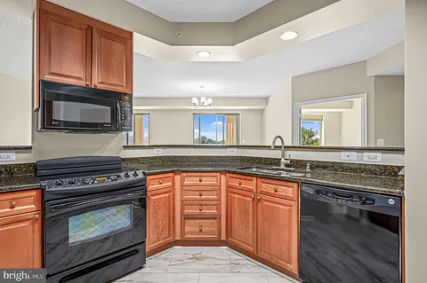 a kitchen with granite countertop a stove top oven a sink dishwasher and wooden cabinets with wooden floor