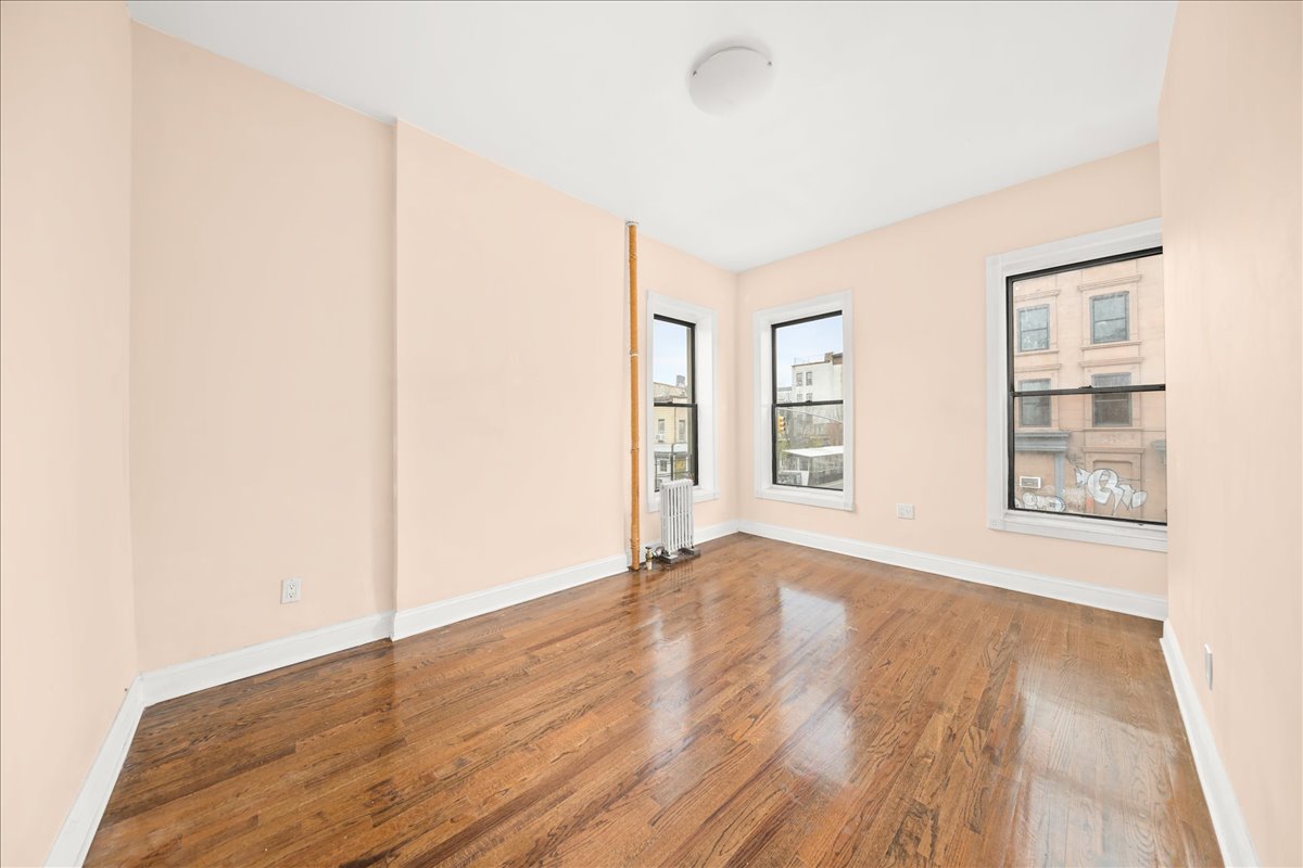 478 Halsey Street, Unit 1 Brooklyn, NY 11233 - Photo 7 of 10 an empty room with wooden floor and windows