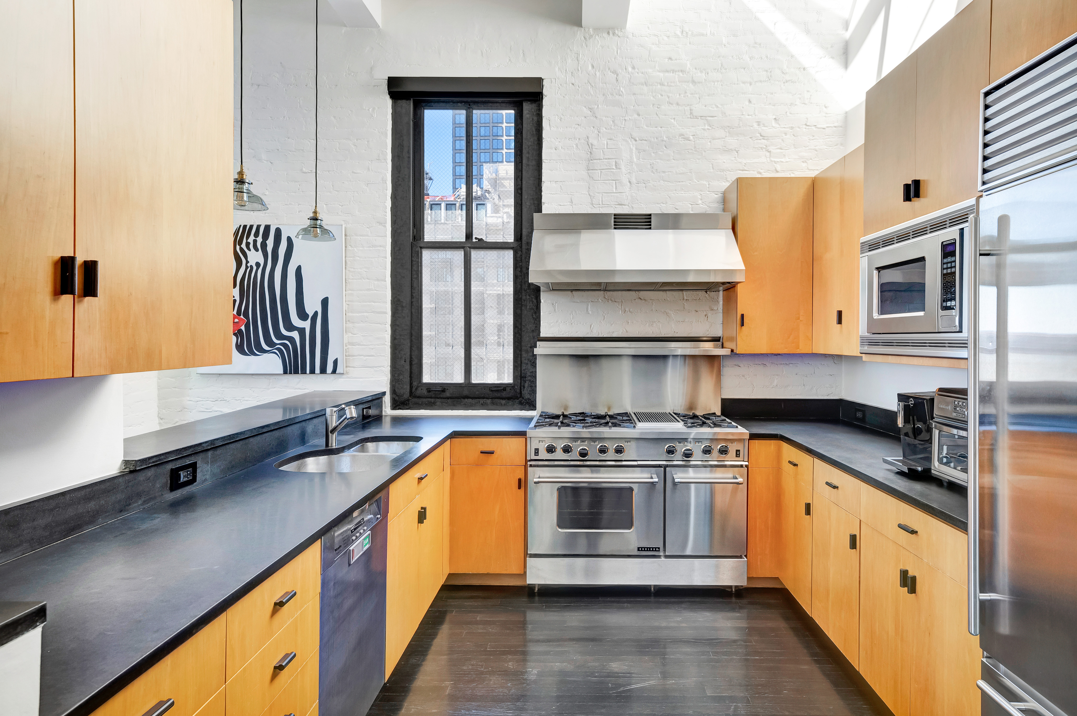 448 West 37th Street, Unit 11G/12G Manhattan, NY 10018 - Photo 7 of 17 a kitchen with stainless steel appliances a stove sink and cabinets