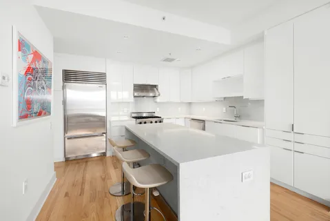 a kitchen that has a lot of cabinets and wooden floor