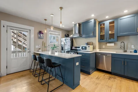 a kitchen with stainless steel appliances granite countertop a sink dishwasher a stove a refrigerator and island with wooden floor