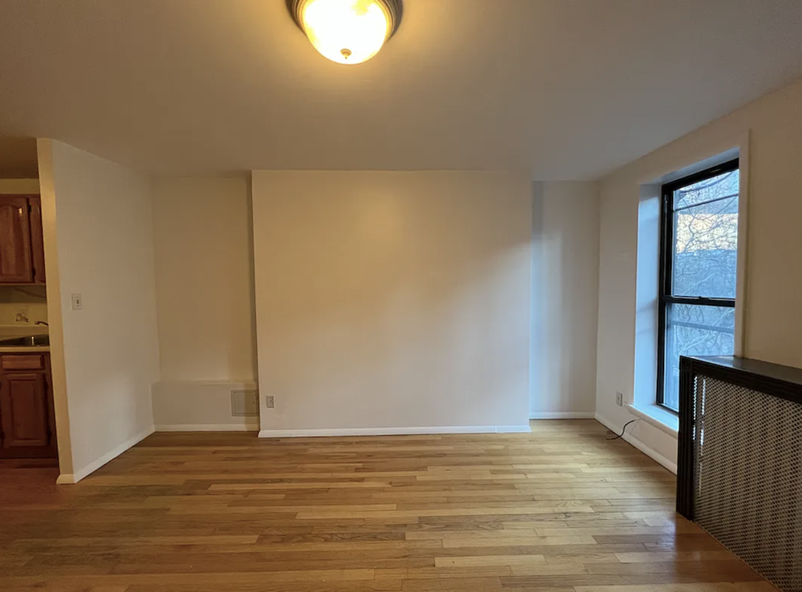 446 West 46th Street, Unit 12 Manhattan, NY 10036 - Photo 4 of 18 a view of an empty room with wooden floor and a window
