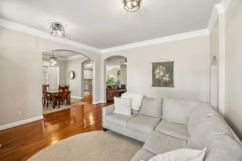 a living room with furniture and a dining table with wooden floor