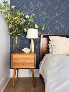 a bed sitting in a bedroom next to a lamp with a potted plant