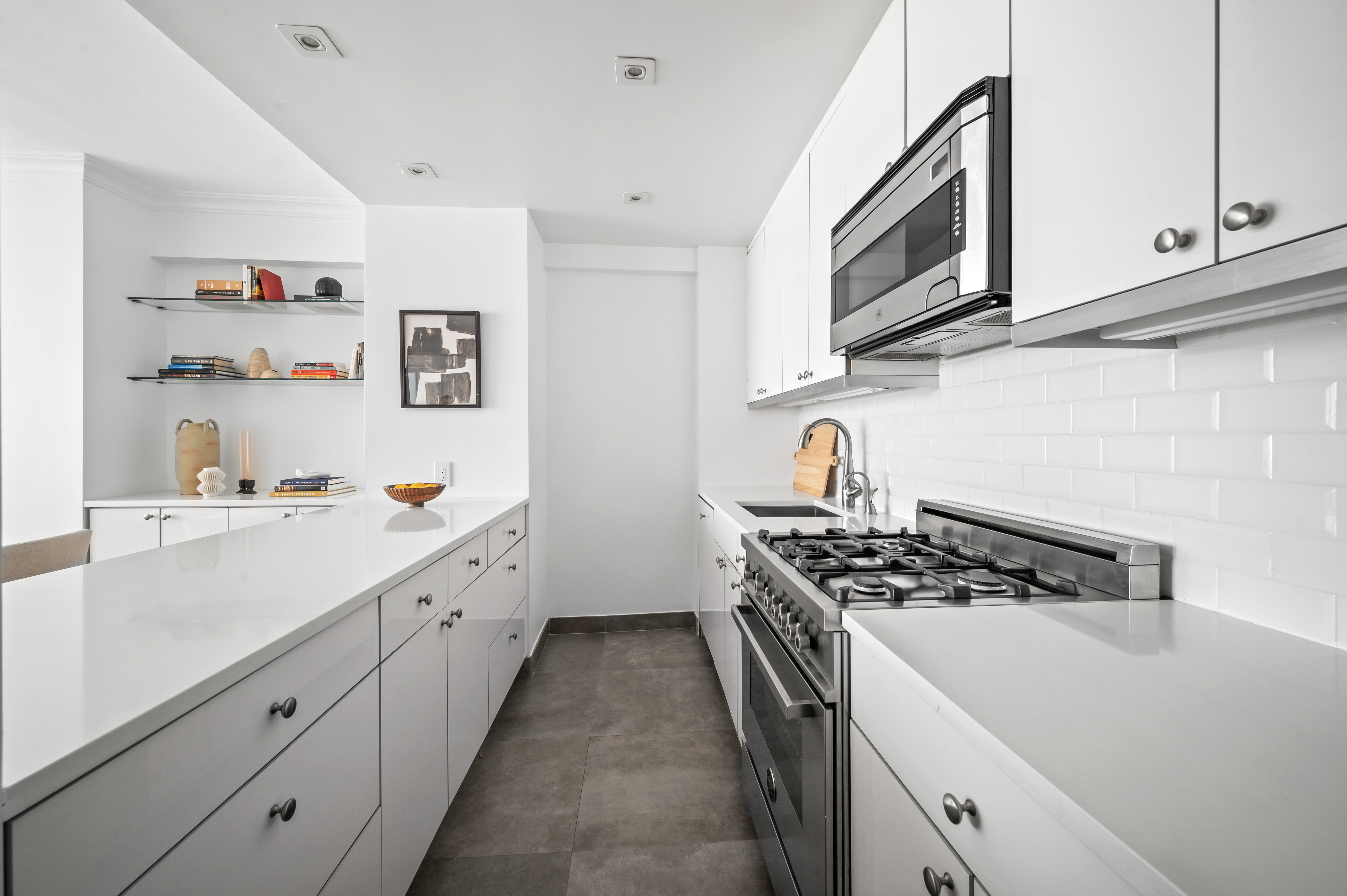 166 East 63rd Street, Unit 2J Manhattan, NY 10065 - Photo 7 of 14 a kitchen with stainless steel appliances granite countertop a stove a sink and a microwave