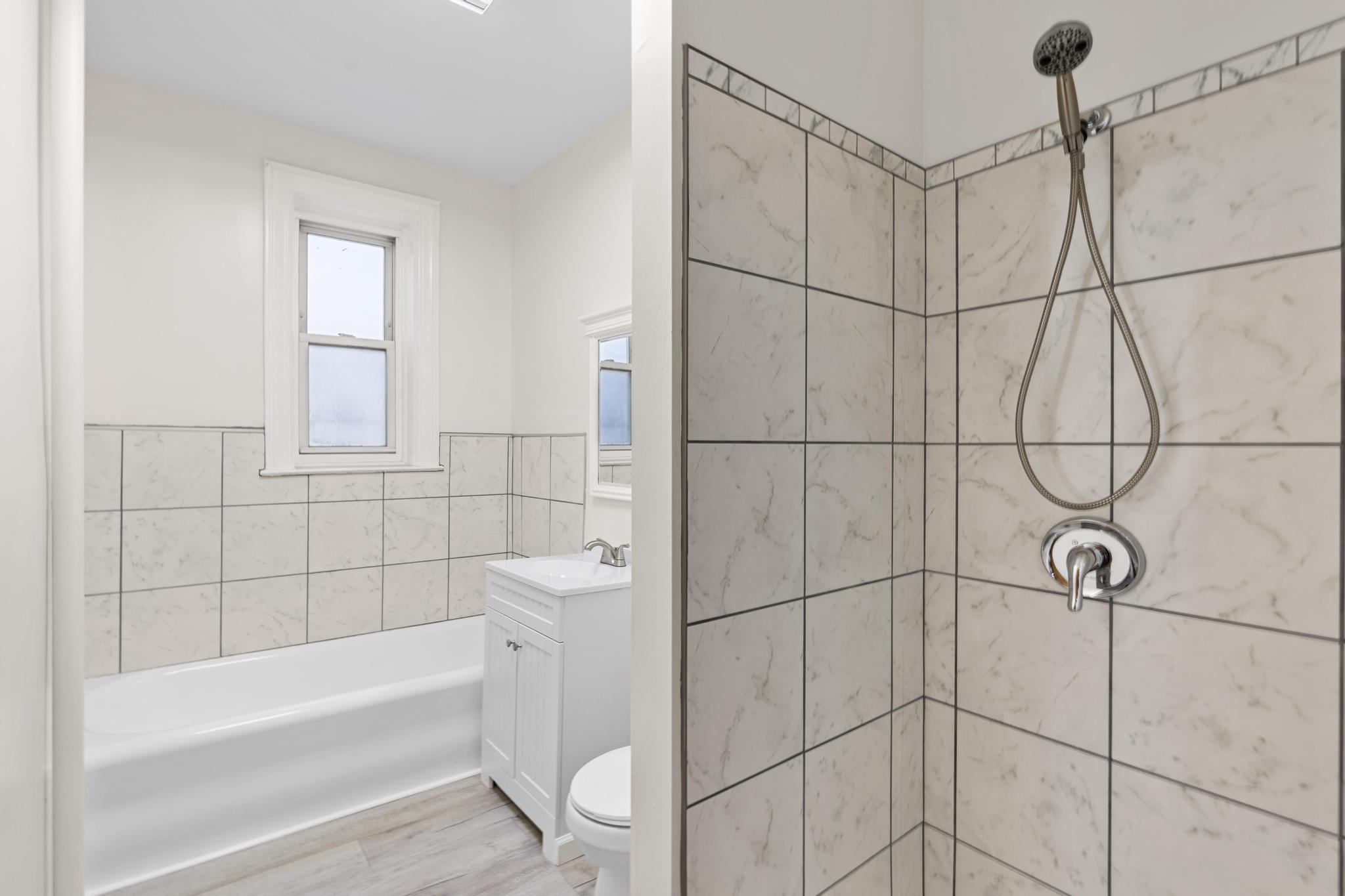 4513 Snyder Avenue Brooklyn, NY 11203 - Photo 4 of 13 a bathroom with a bathtub a window and shower