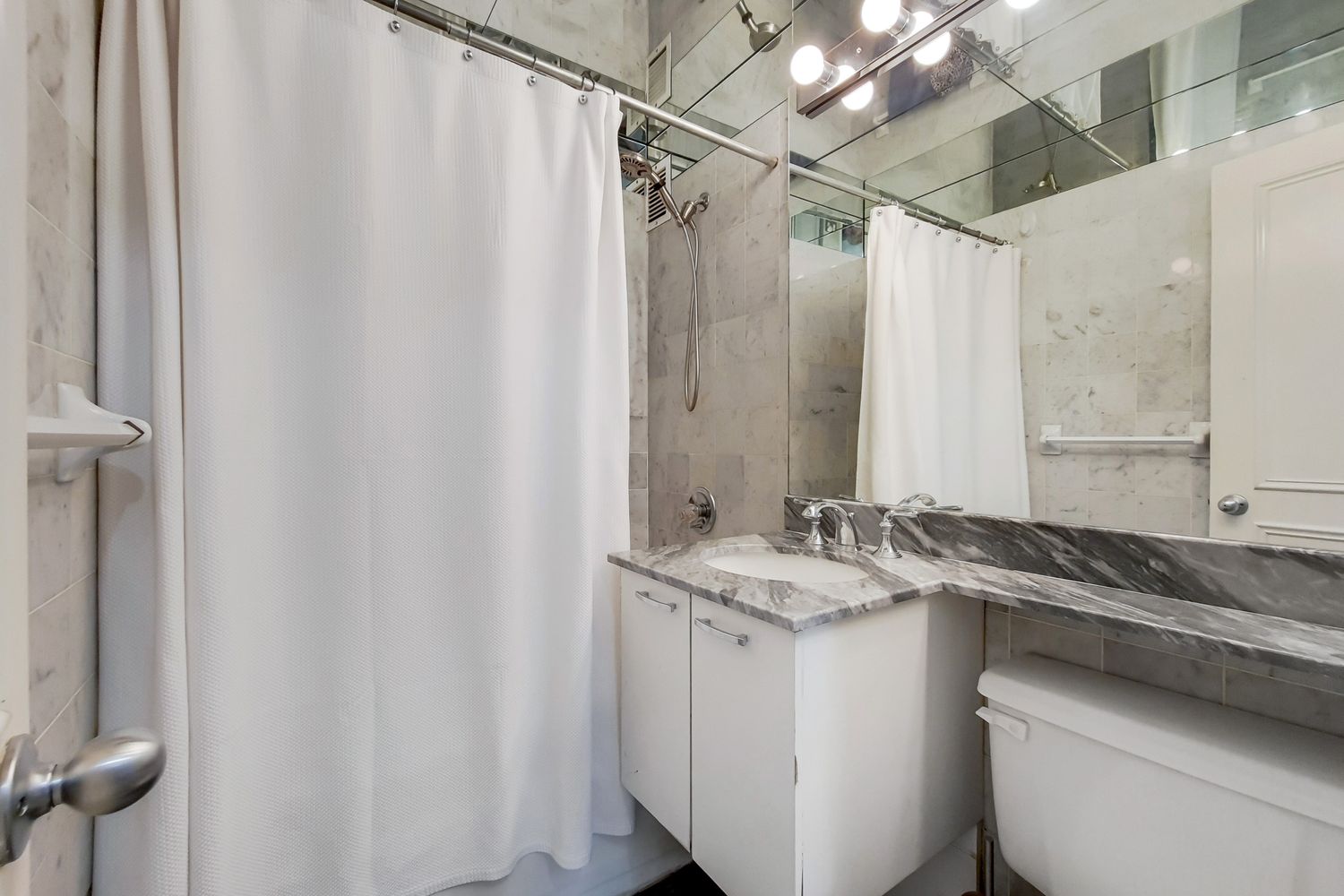 225 East 57th Street, Unit 5K Manhattan, NY 10022 - Photo 9 of 11 a bathroom with a granite countertop sink and a mirror