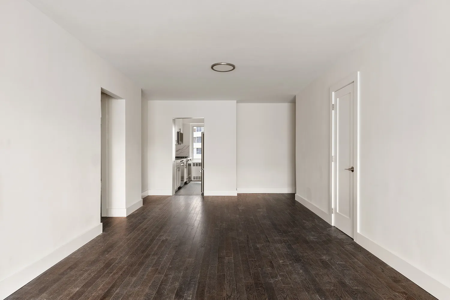 a view of an empty room with wooden floor & cabinets