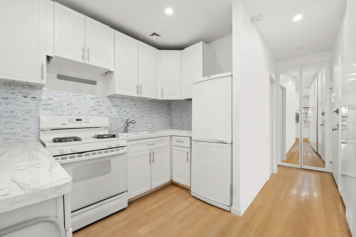 35 East 10th Street, Unit 2G Manhattan, NY 10003 - Photo 5 of 11 a kitchen with cabinets appliances and wooden floor