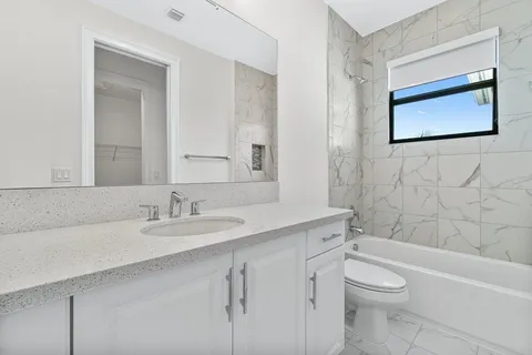 a bathroom with a granite countertop toilet a sink a mirror and a bathtub