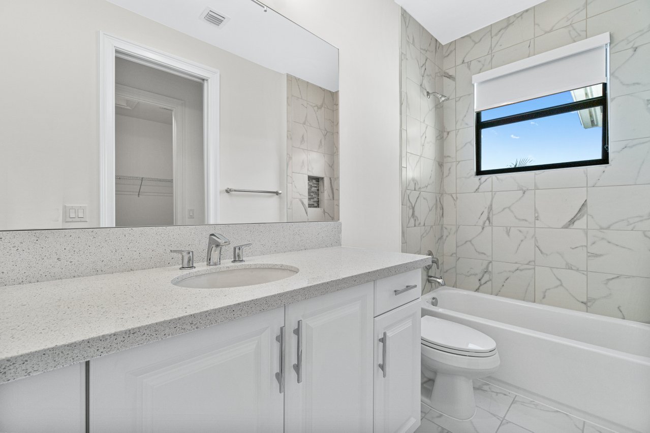 17352 Rosella Road Boca Raton, FL 33496 - Photo 18 of 41 a bathroom with a granite countertop toilet a sink a mirror and a bathtub
