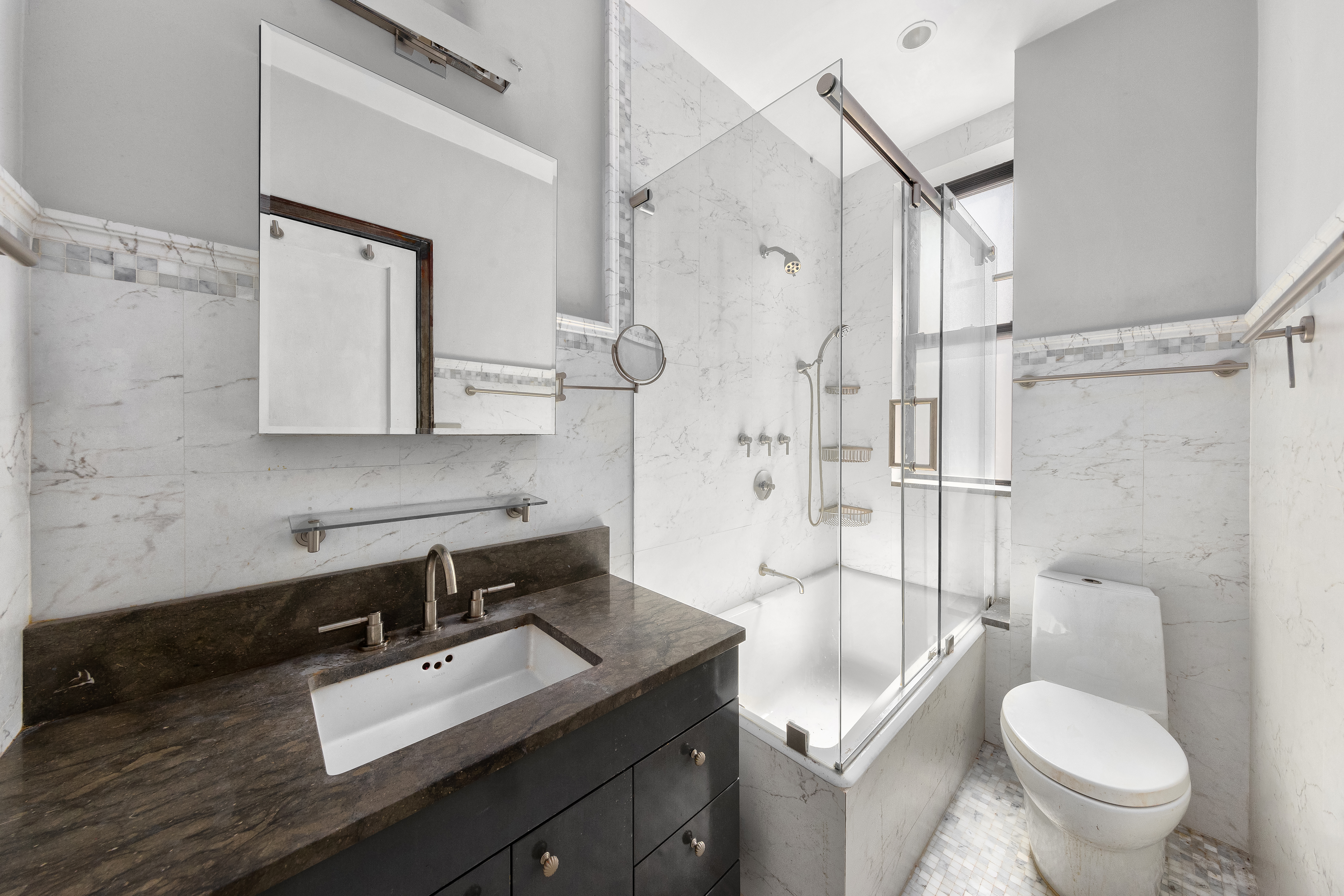 205 West 54th Street, Unit 10E Manhattan, NY 10019 - Photo 5 of 8 a bathroom with a sink toilet vanity and shower