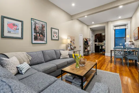 a living room with furniture a wooden floor and kitchen view