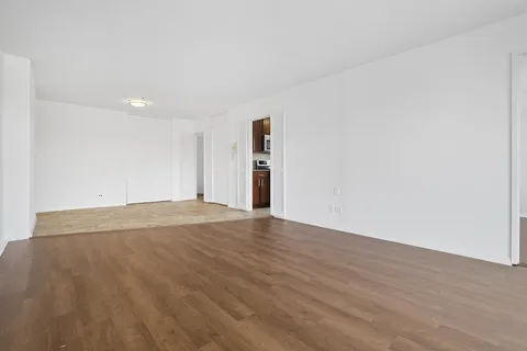 a view of empty room with wooden floor and window