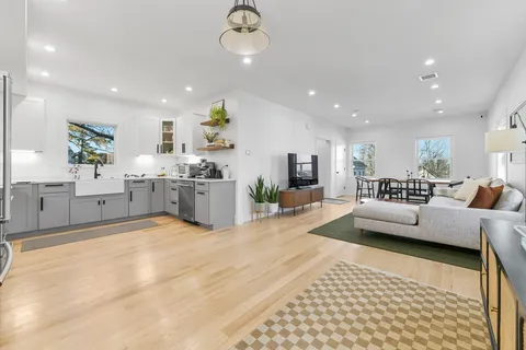 a living room with furniture and a dining table with wooden floor