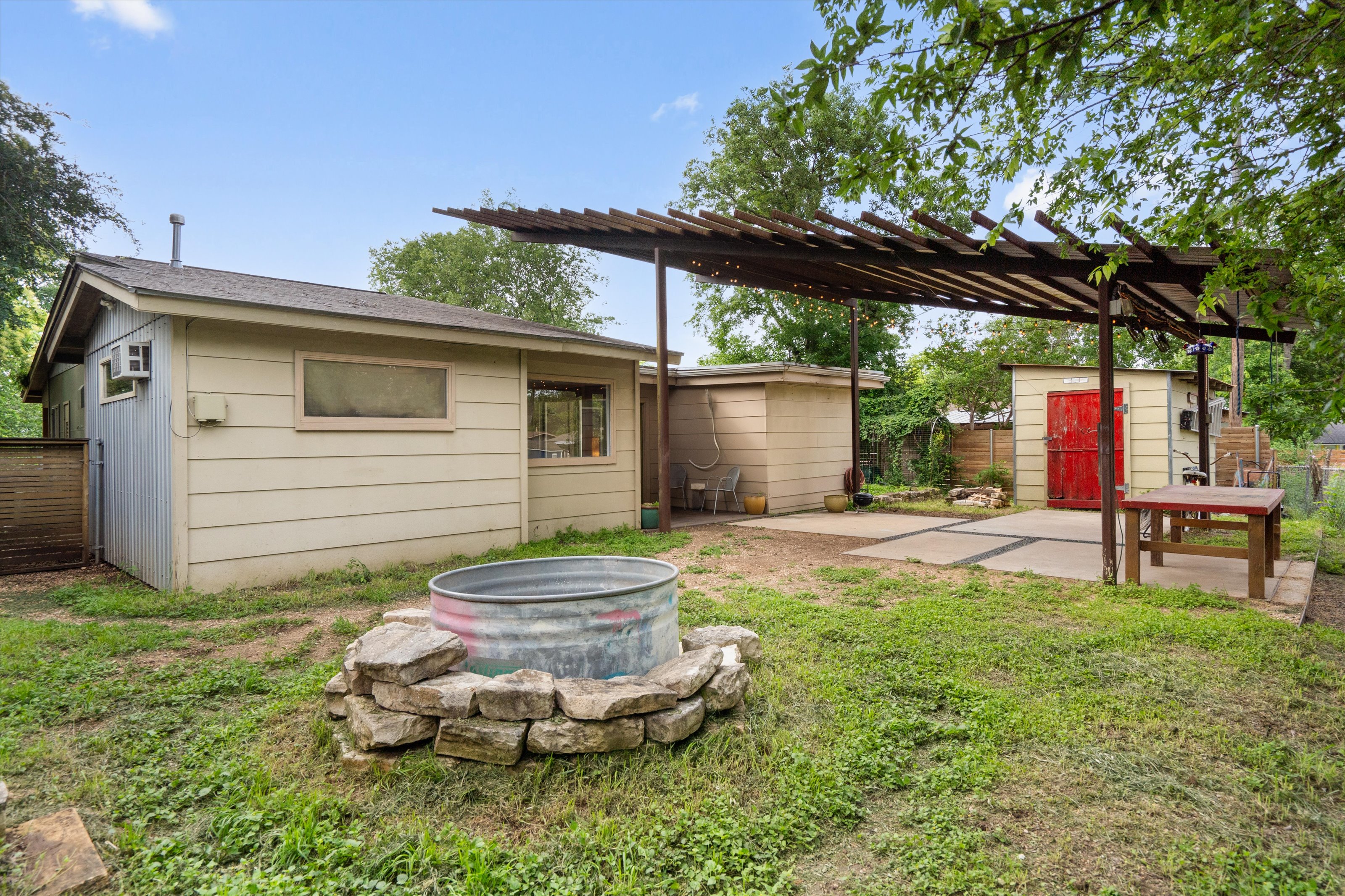 4614 Jinx Avenue Austin, TX 78745 - Photo 33 of 40 a backyard of house with table and chairs under an umbrella with a large tree