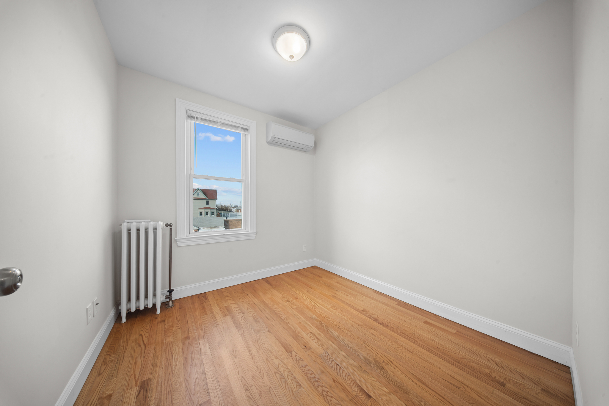 52-19 69th Street Queens, NY 11378 - Photo 21 of 35 an empty room with wooden floor and windows