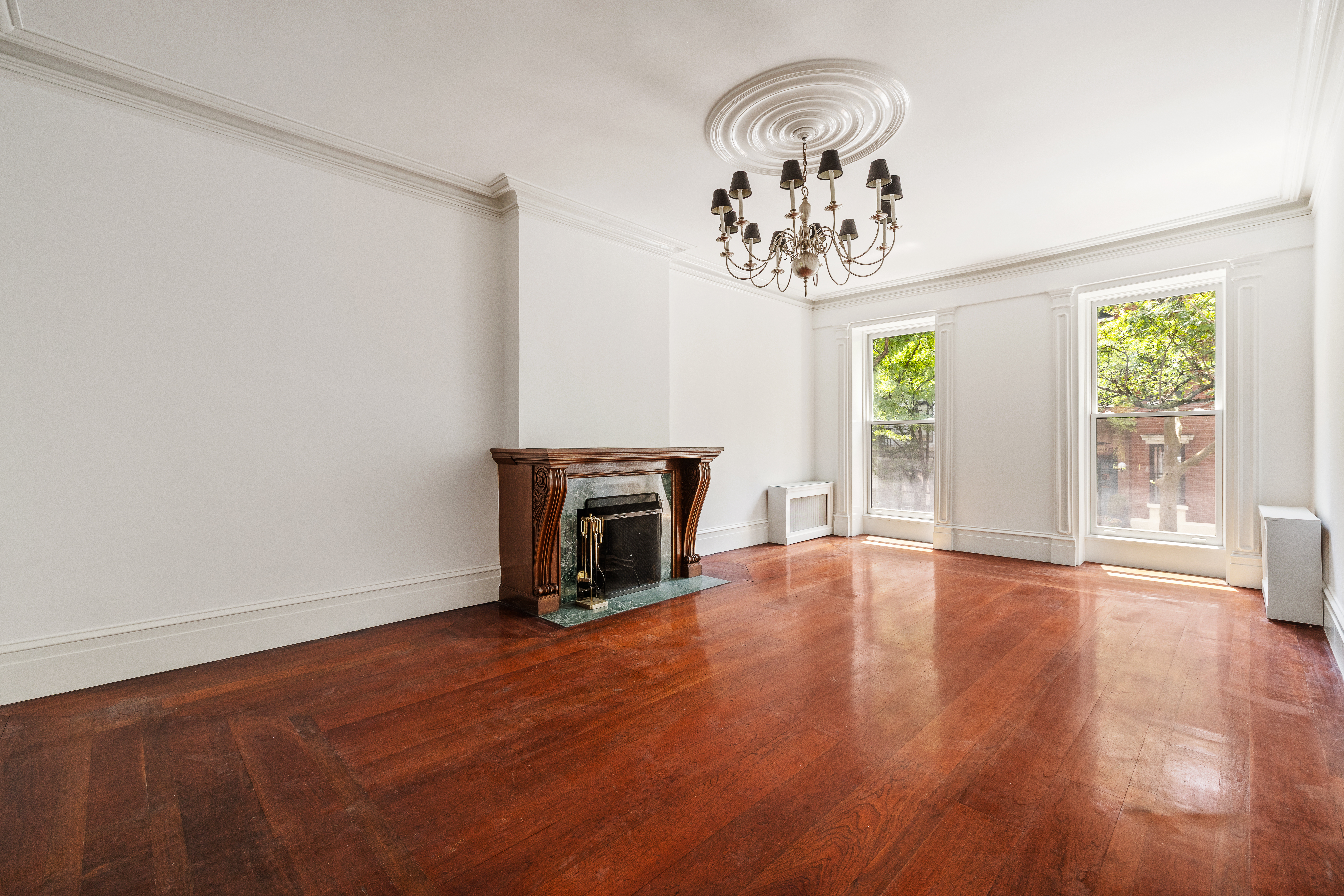 225 West 22nd Street Manhattan, NY 10011 - Photo 2 of 12 an empty room with wooden floor fireplace and windows