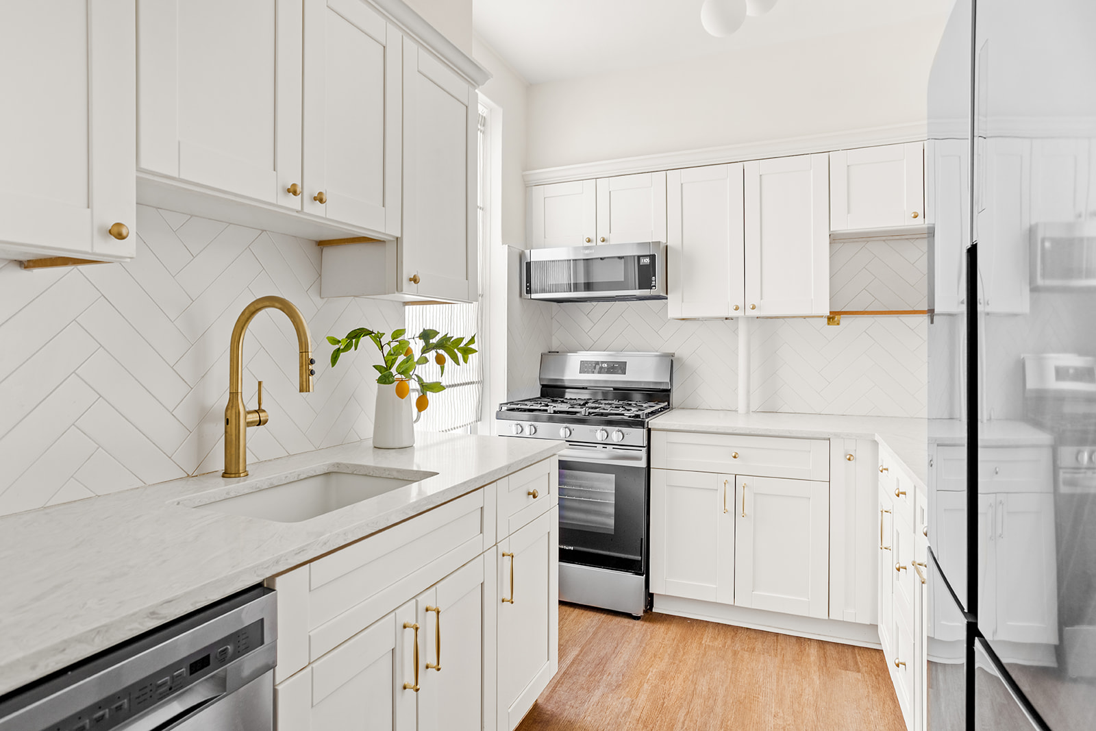 37-51 84th Street, Unit 21 Queens, NY 11372 - Photo 3 of 10 a kitchen with stainless steel appliances granite countertop a sink a stove a refrigerator with white cabinets and wooden floor