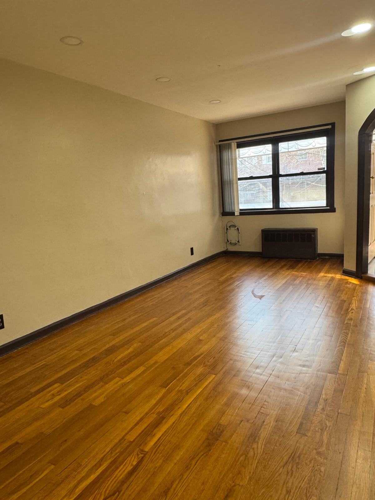 647 East 82nd Street, Unit 2 Brooklyn, NY 11236 - Photo 6 of 6 an empty room with wooden floor and windows