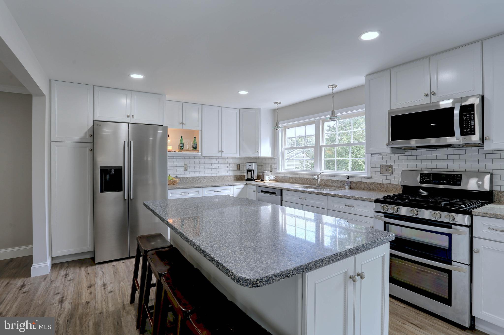 6257 Fairbourne Court Hanover, MD 21076 - Photo 9 of 47 a kitchen with stainless steel appliances granite countertop a sink a stove a microwave a center island and a window