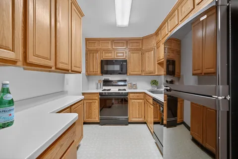a utility room with stainless steel appliances granite countertop a refrigerator and a sink