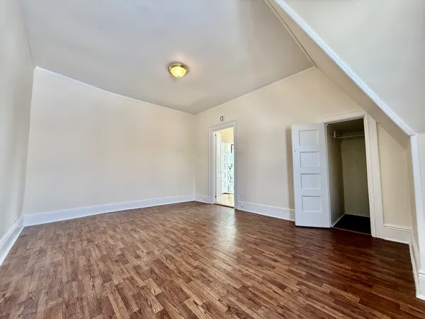 a view of an empty room with wooden floor and closet