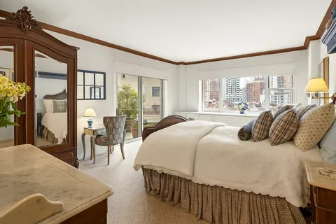 a bedroom with a bed a table and large windows