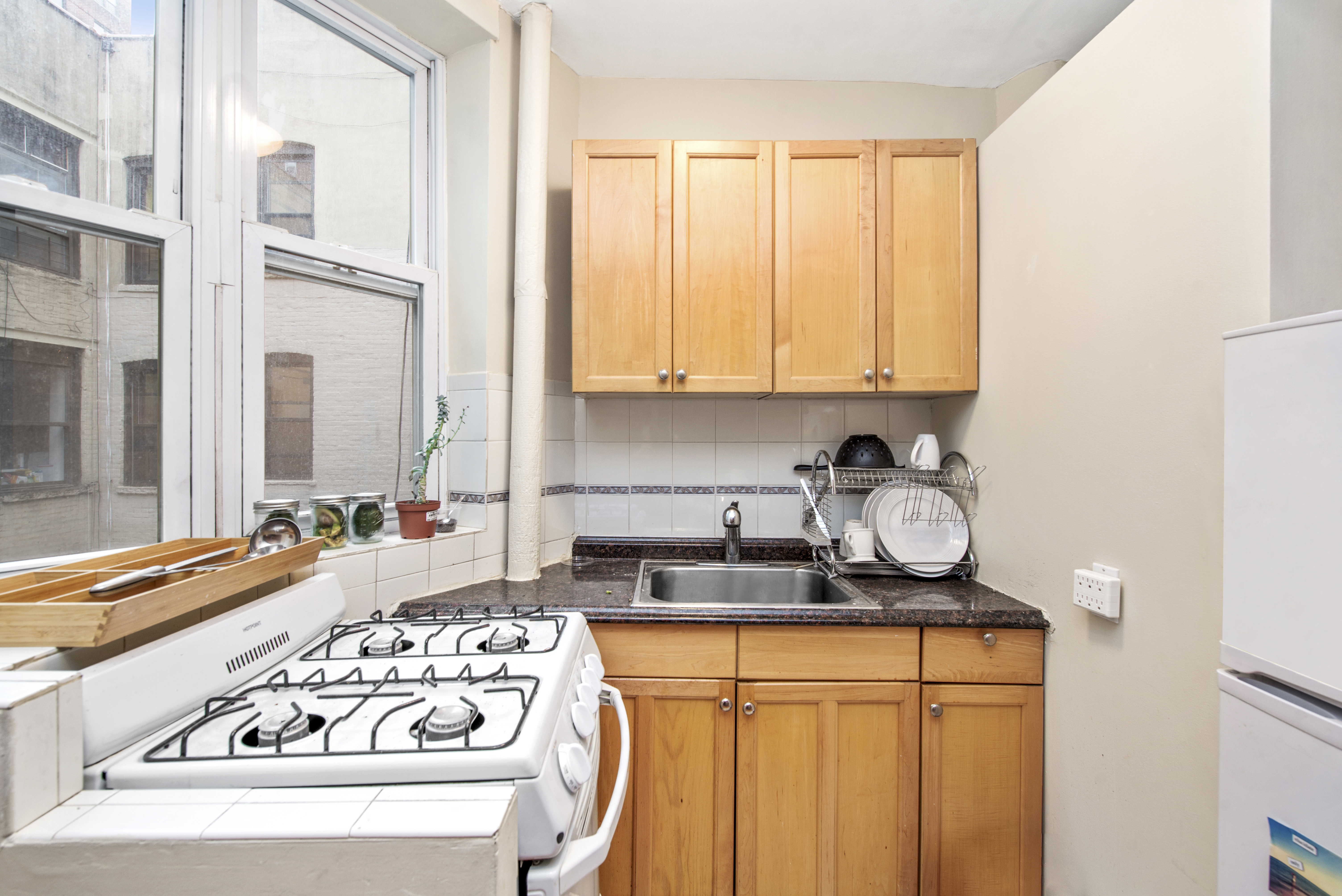 309 East 95th Street, Unit 23 Manhattan, NY 10128 - Photo 3 of 6 a kitchen with stainless steel appliances granite countertop a stove a sink and a refrigerator with wooden cabinets