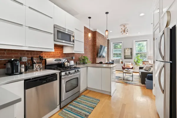 a kitchen with stainless steel appliances granite countertop a refrigerator a sink dishwasher a stove and white cabinets with wooden floor