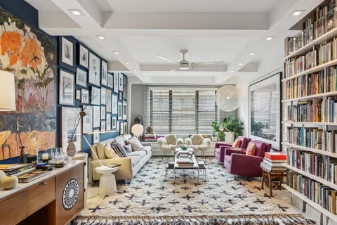 a living room with furniture lots of books and a book shelf