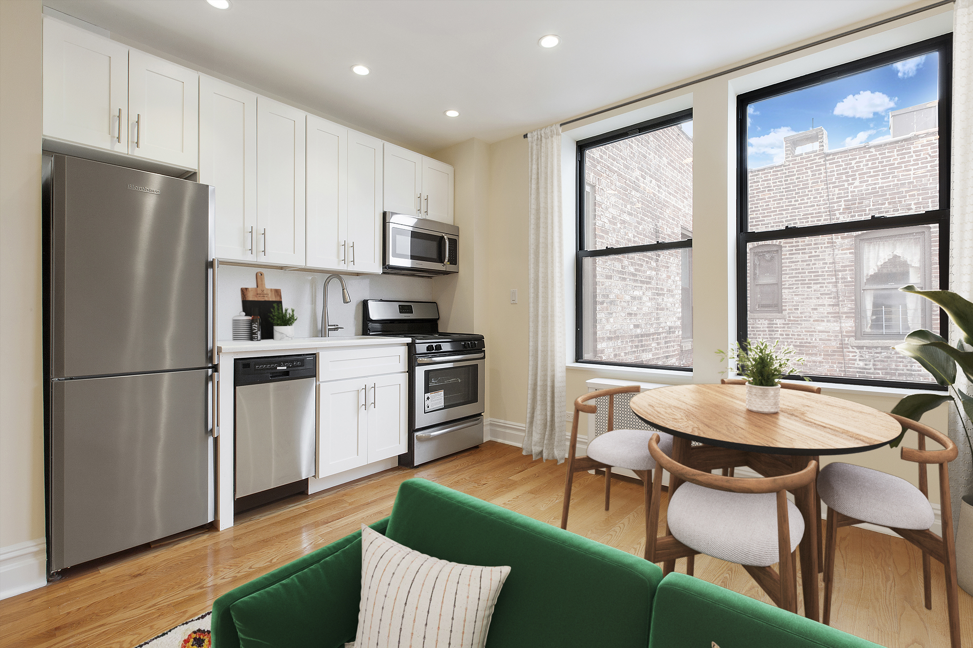 750 Riverside Drive, Unit 6B Manhattan, NY 10031 - Photo 3 of 9 a kitchen with stainless steel appliances granite countertop a stove a refrigerator a sink a dining table and chairs with wooden floor