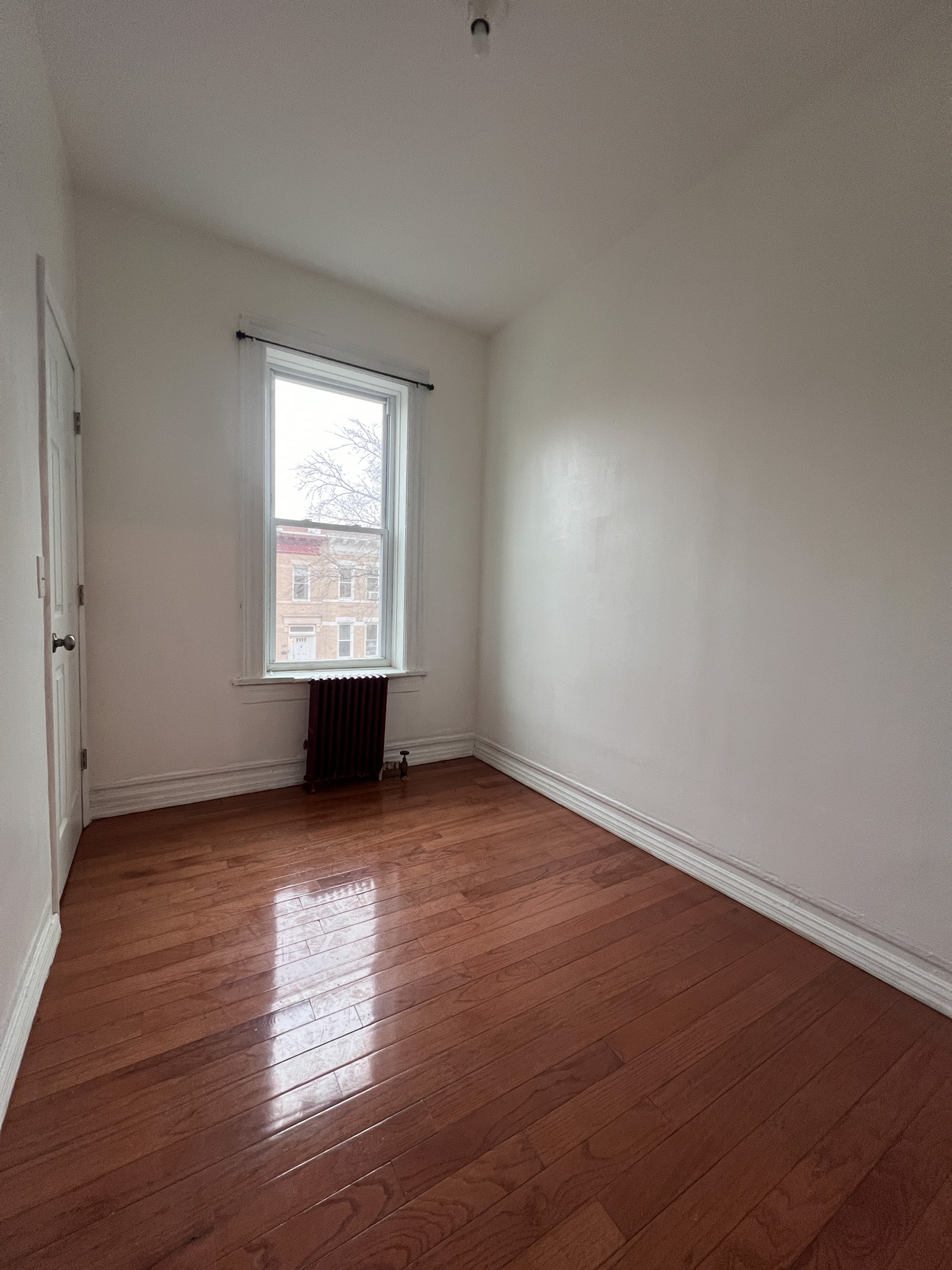 236 45th Street, Unit 2 Brooklyn, NY 11220 - Photo 6 of 8 a view of an empty room with wooden floor and a window