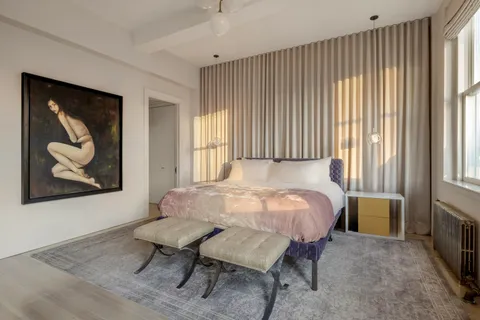 a bed sitting in a spacious bedroom next to a window