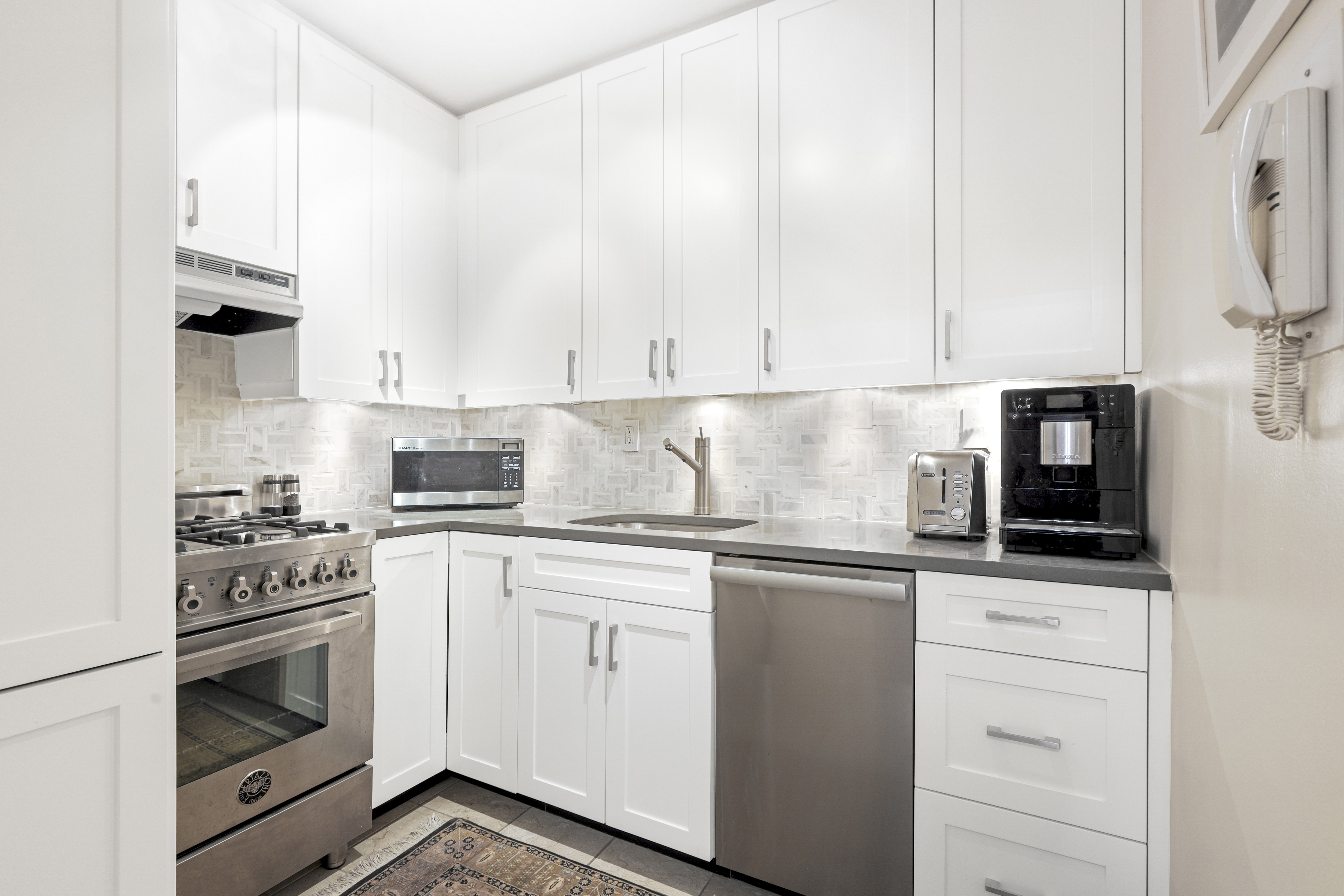 165 West 66th Street, Unit 2S Manhattan, NY 10023 - Photo 3 of 7 a kitchen with granite countertop white cabinets and white appliances