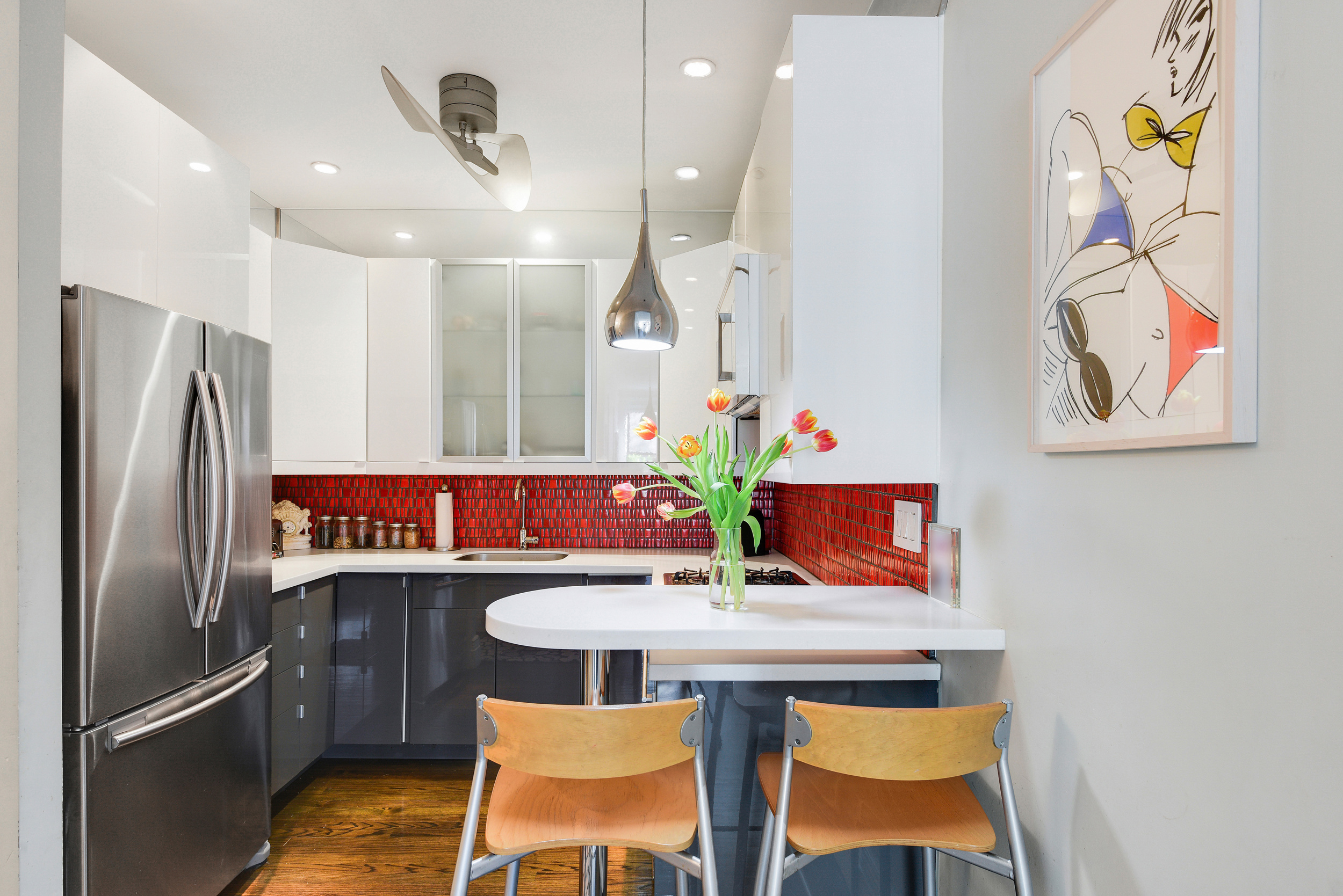 253 West 16th Street, Unit 3A Manhattan, NY 10011 - Photo 4 of 13 a kitchen with stainless steel appliances granite countertop a dining table chairs and a refrigerator