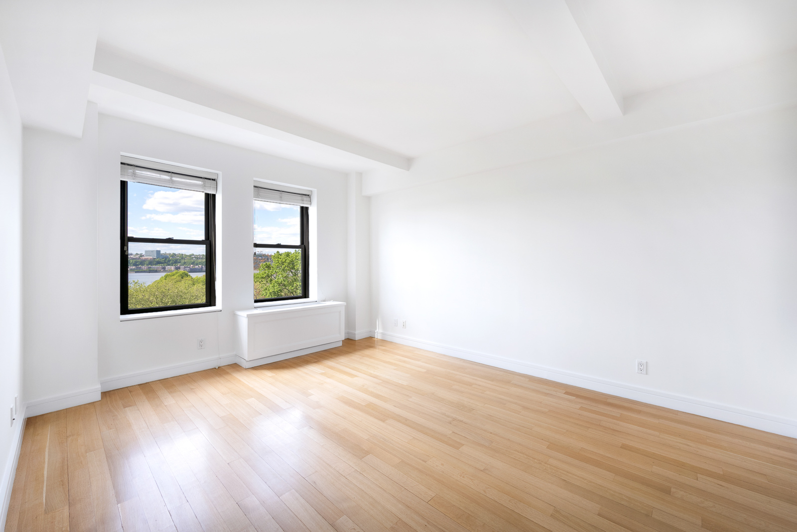230 Riverside Drive, Unit 8C Manhattan, NY 10025 - Photo 4 of 10 an empty room with wooden floor and windows