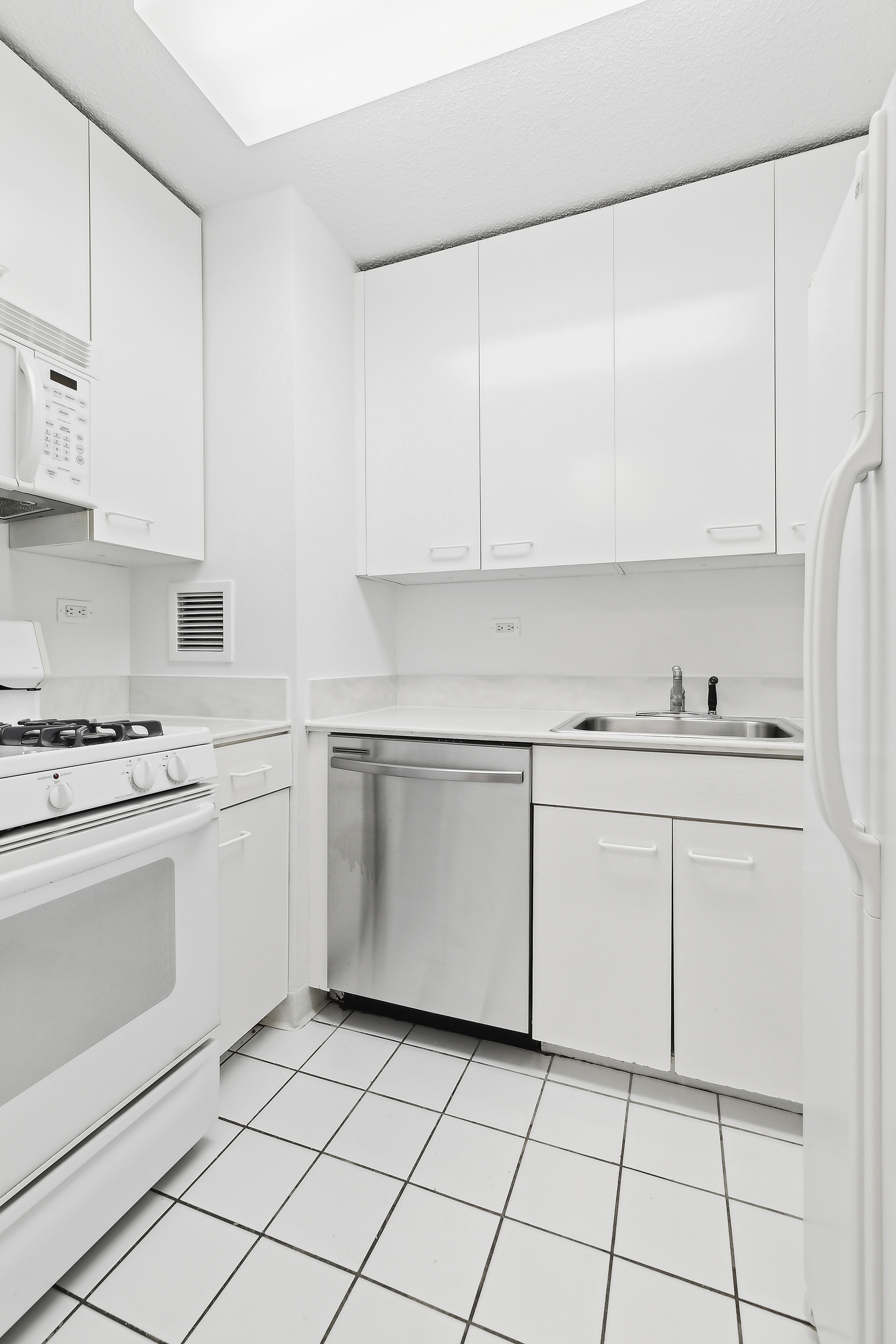 330 East 38th Street, Unit 38G Manhattan, NY 10016 - Photo 3 of 7 a kitchen with white cabinets a sink and white appliances