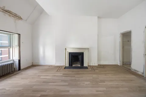 an empty room with window and fireplace
