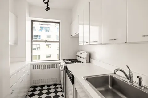 a kitchen with a sink a stove and white cabinets