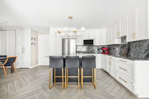 a kitchen with stainless steel appliances kitchen island granite countertop a table chairs sink and cabinets