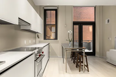 a kitchen with a sink a stove and white cabinets next to a window