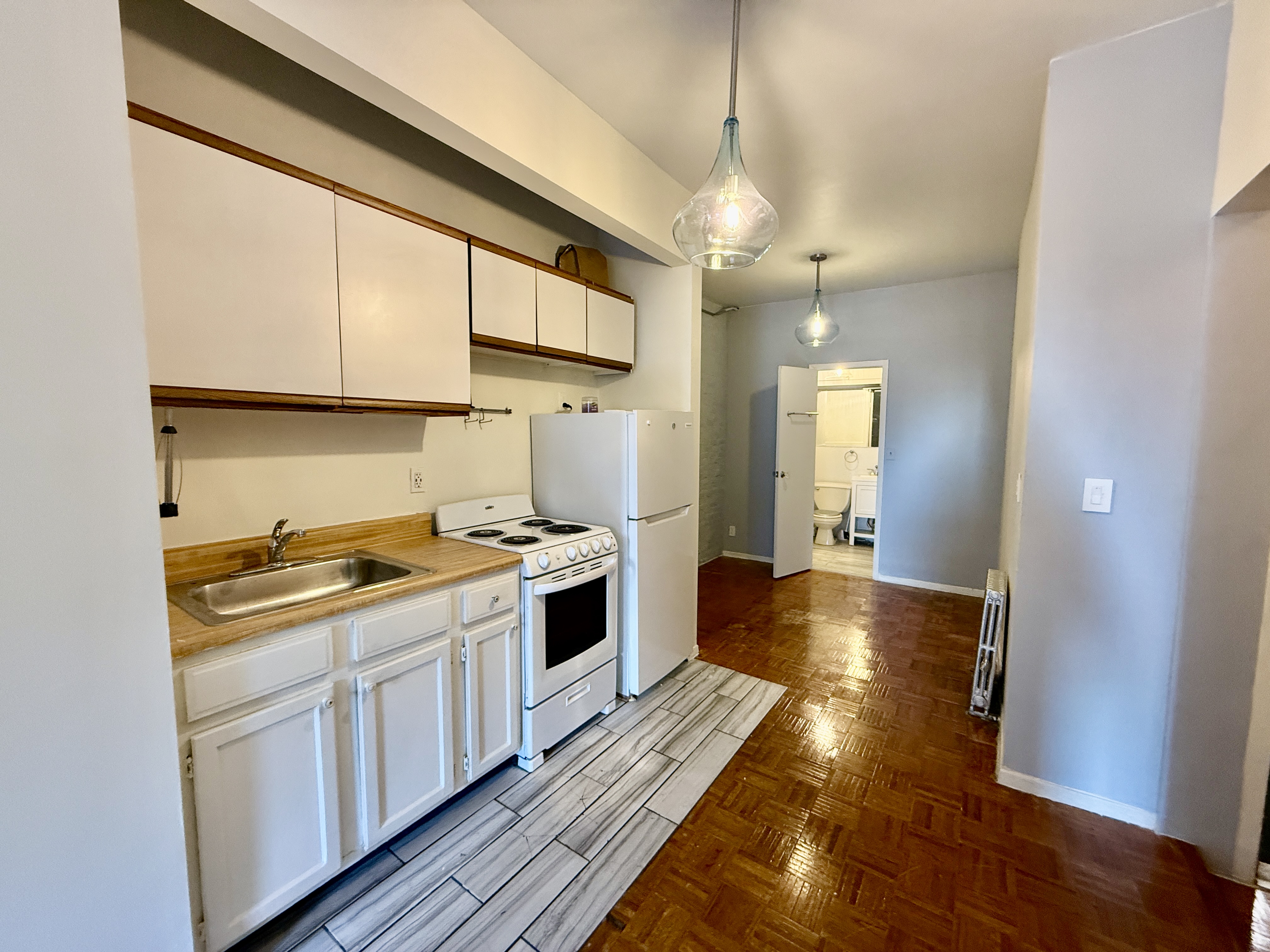 344 East 61st Street, Unit 16 Manhattan, NY 10065 - Photo 4 of 8 a kitchen with a stove a sink and wooden floor