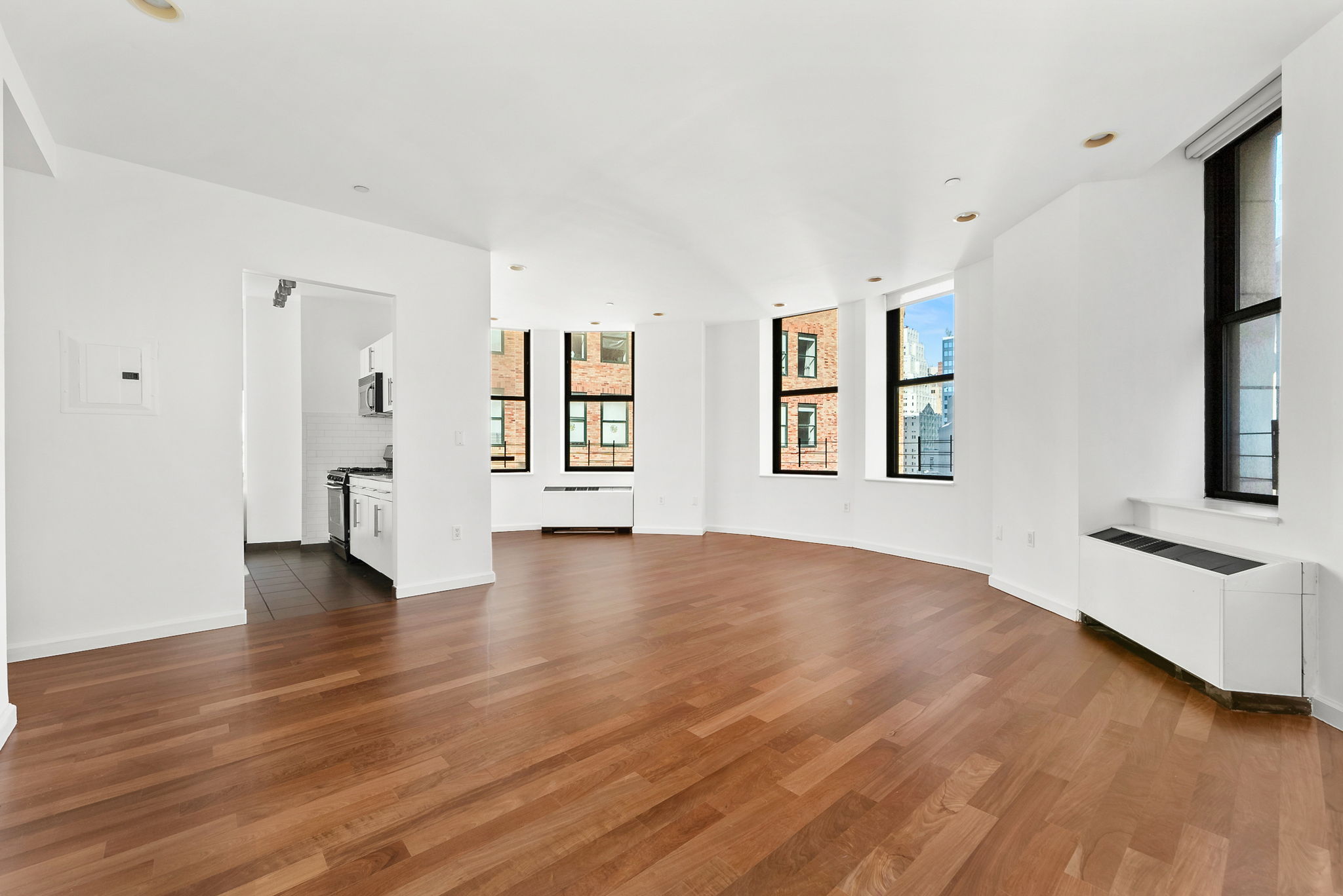 1 Wall Street Court, Unit 1405 Manhattan, NY 10005 - Photo 1 of 19 an empty room with wooden floor and windows