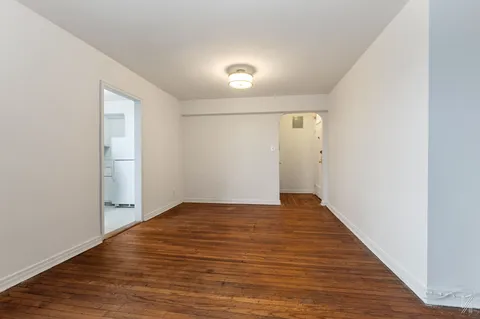a view of an empty room with wooden floor and closet