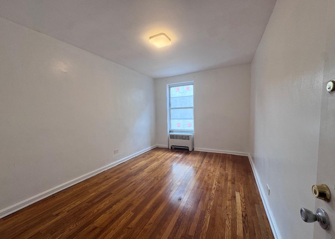 123 Avenue A, Unit 4 Manhattan, NY 10009 - Photo 7 of 14 a view of an empty room with a window and wooden floor