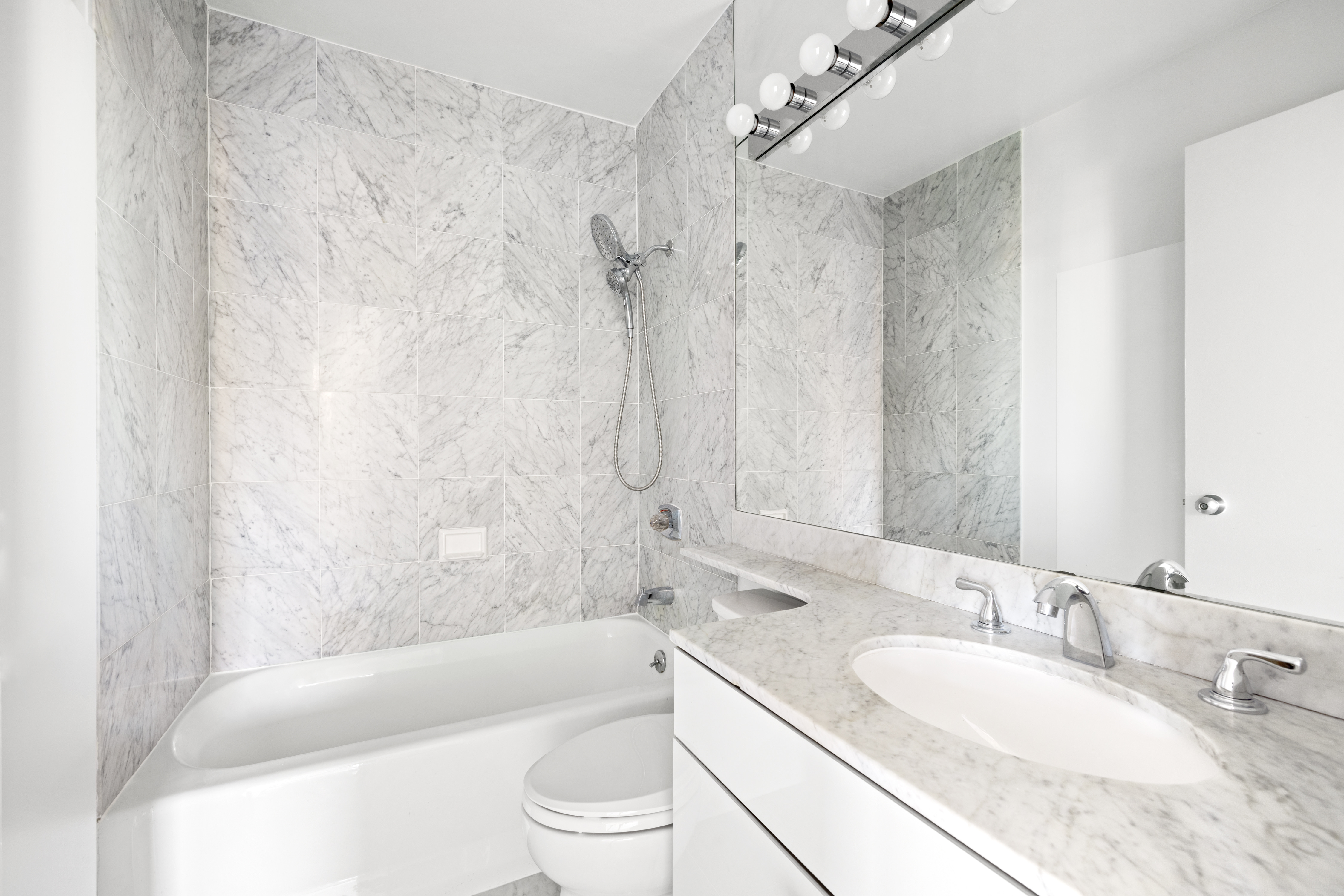 200 East 89th Street, Unit 29D Manhattan, NY 10128 - Photo 7 of 16 a bathroom with a granite countertop sink a toilet a mirror a bathtub and shower