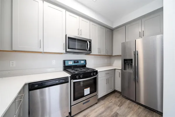 a kitchen with stainless steel appliances white cabinets white stove a microwave and a refrigerator