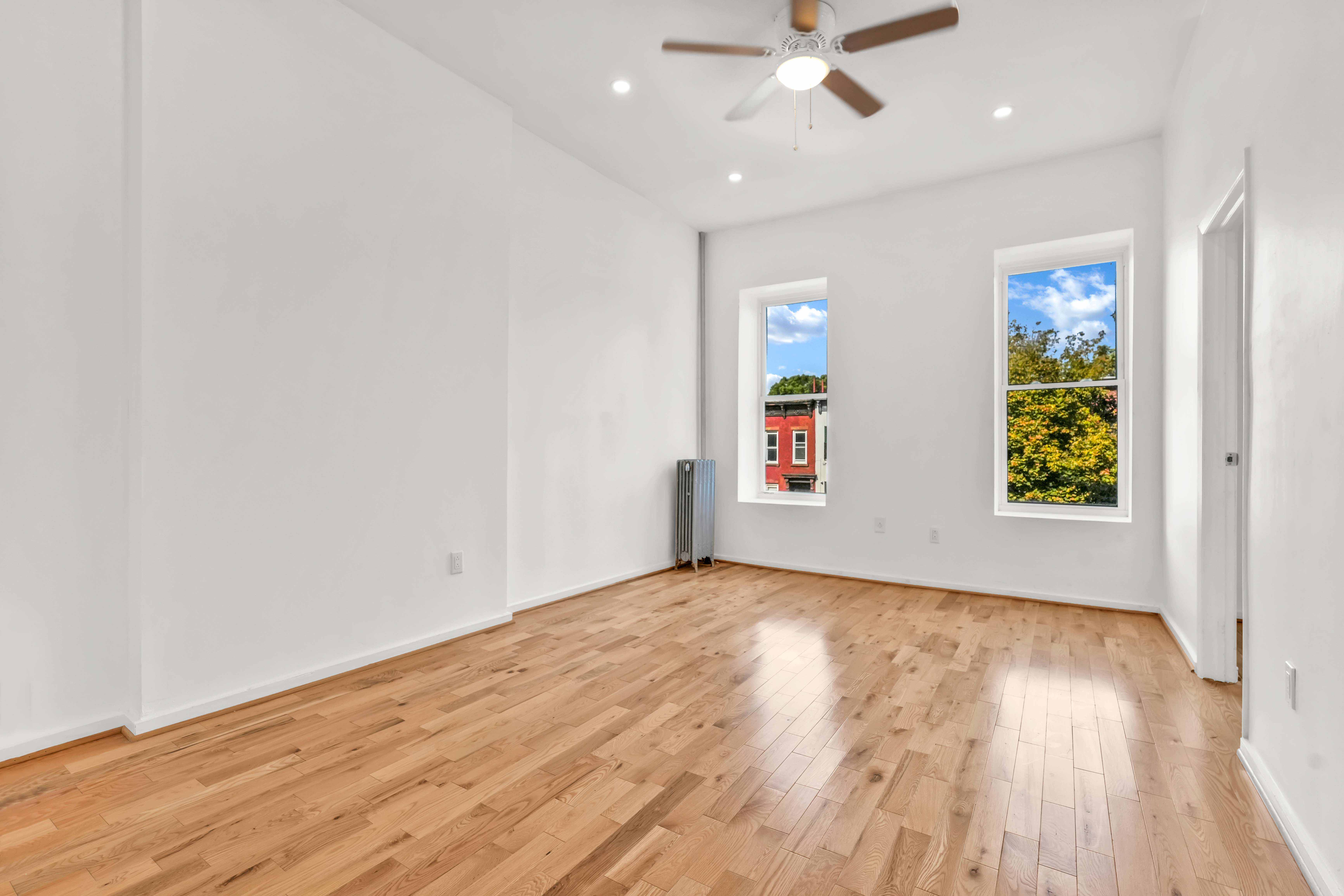 238 Vernon Avenue, Unit 2 Brooklyn, NY 11206 - Photo 3 of 21 an empty room with wooden floor chandelier fan and windows