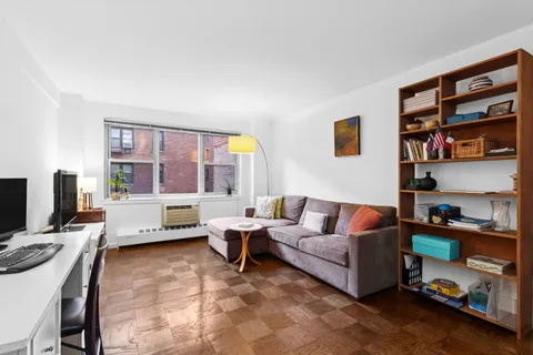 a living room with furniture a bookshelf and a window